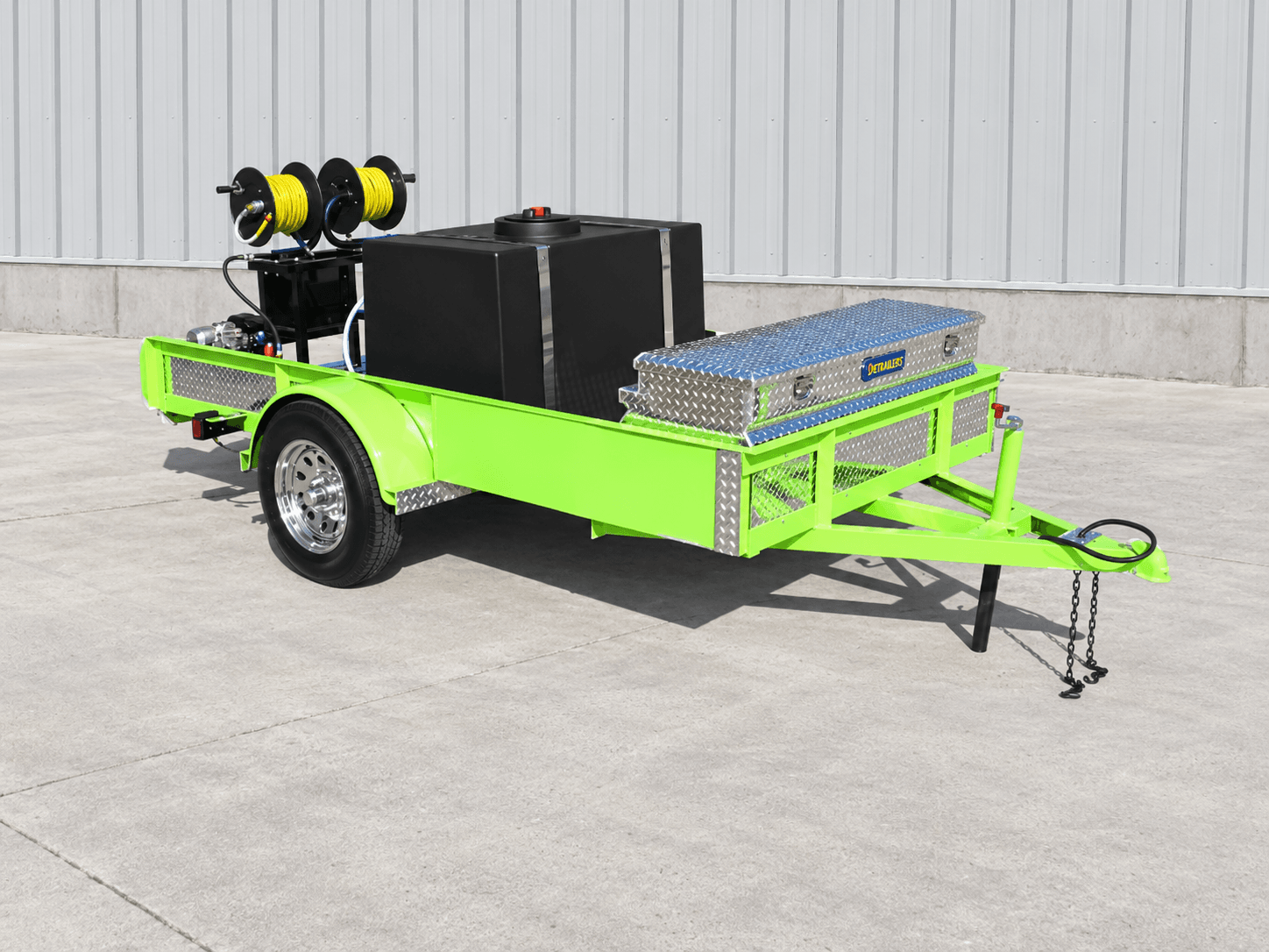 Green DB Series open utility trailer with a black water tank, twin yellow hose reels, and an aluminum toolbox on a single axle